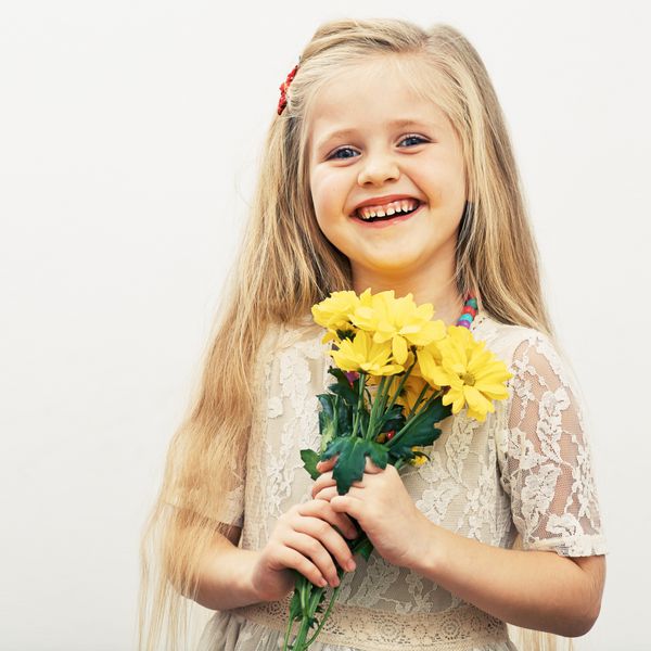 دختر خندان گلهای زرد در دست دارد