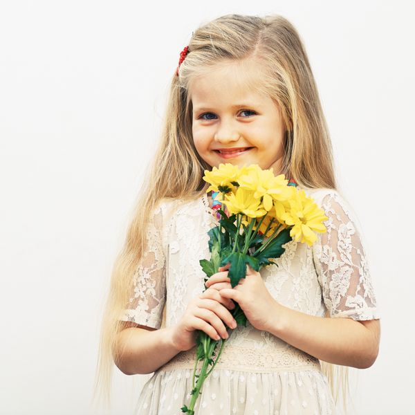 دختر خندان گلهای زرد در دست دارد