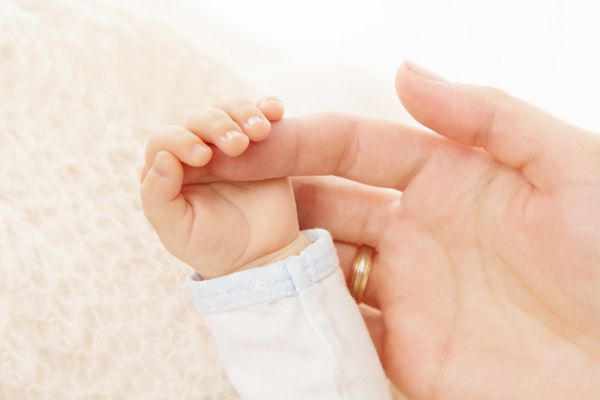 دست نوزاد تازه متولد شده که انگشت مادر والدین را گرفته است