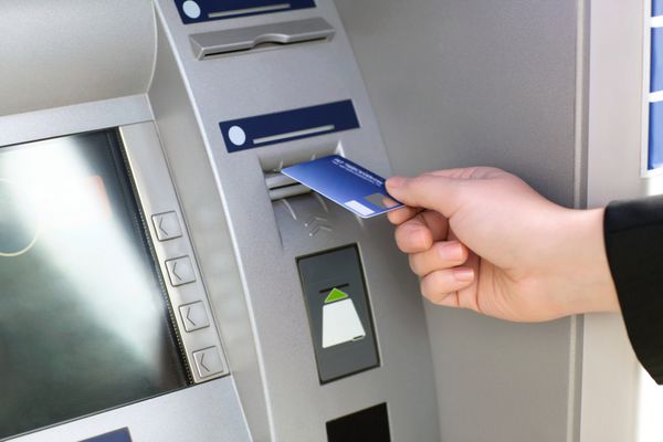 تاجر دست مردانه کارت اعتباری را در دستگاه خودپرداز قرار می دهد