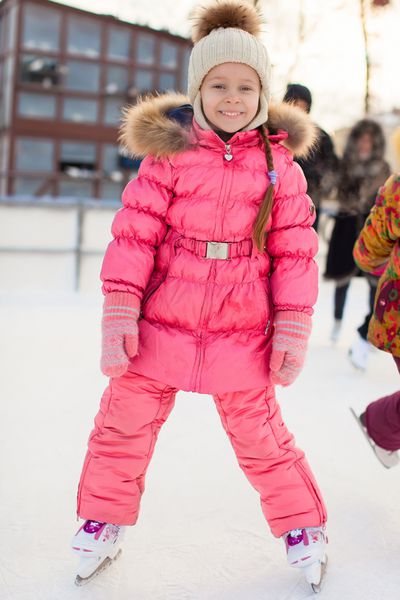 دختر کوچولوی دوست داشتنی که روی پیست یخ اسکیت می کند