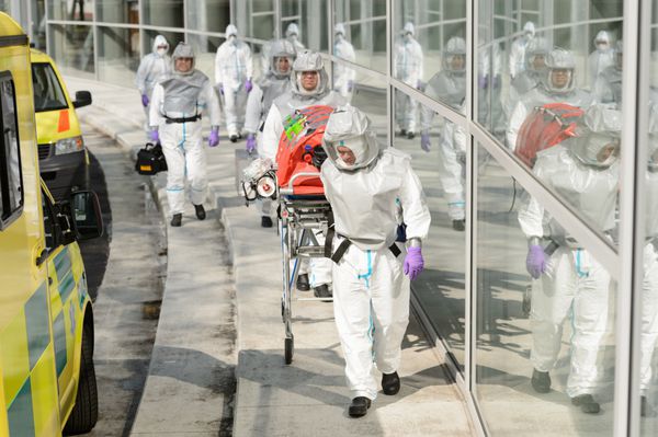 تیم پزشکی خطرات زیستی در حال پیاده روی به سمت ساختمان