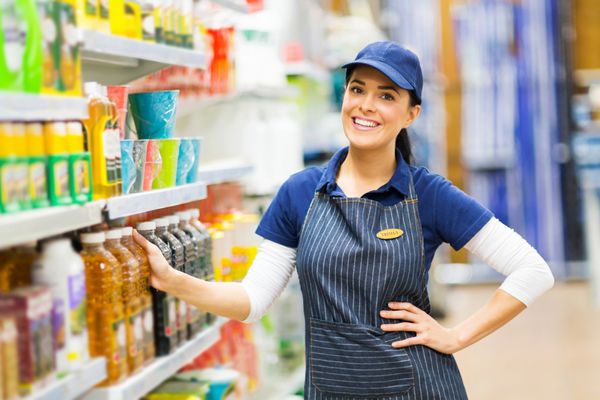 زن فروشنده سوپرمارکت در فروشگاه ایستاده است