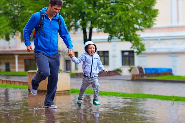 پدر و پسر شادی که زیر باران می دوند