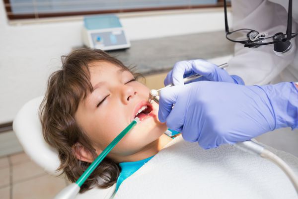 دندانپزشک اطفال در حال معاینه دندان های پسر کوچک
