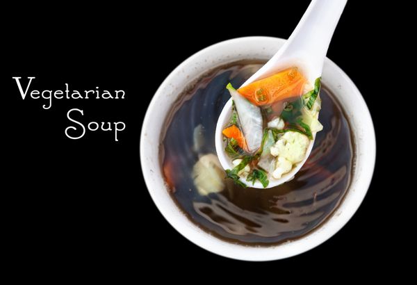 سوپ سنتی گیاهی با قاشق پر از سبزیجات در پس زمینه سیاه sp رایگان برای متن شما
