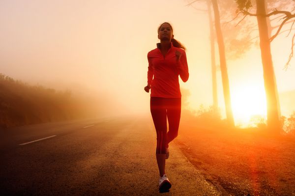 دونده سالم زن دونده صبح زود تمرین طلوع آفتاب در دویدن تمرین در جاده کوهستانی مه آلود نور آفتاب از میان مه حس و عمق جوی به این تصاویر تناسب اندام می دهد