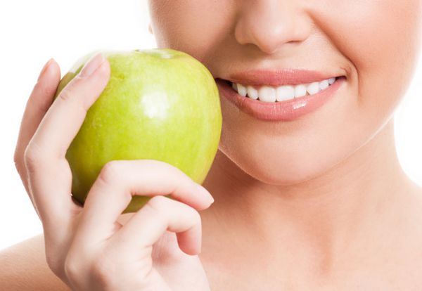 نمای نزدیک از f زنی که یک سیب سبز در دست دارد جدا شده در برابر پس زمینه سفید