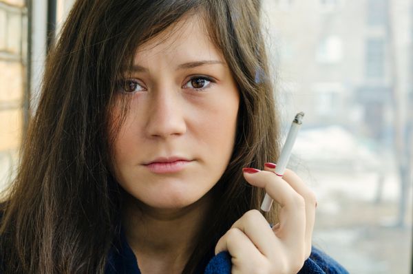 زن جوان واقعی در خیابان سیگار می کشد تمرکز انتخابی