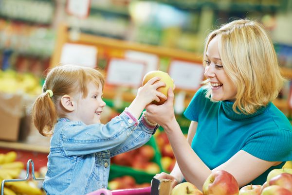 انتخاب سیب زن و دختر کوچک هنگام خرید از سوپرمارکت سبزیجات میوه