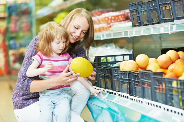 انتخاب سیب زن و دختر کوچک هنگام خرید از سوپرمارکت سبزیجات میوه