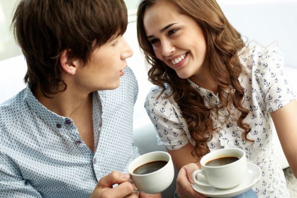 زوج شادی که قهوه می نوشند و با محبت به یکدیگر نگاه می کنند