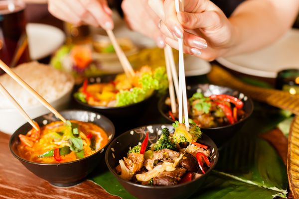 جوانانی که در یک رستوران تایلندی غذا می خورند آنها با چاپستیک نمای نزدیک روی دست و غذا غذا می خورند