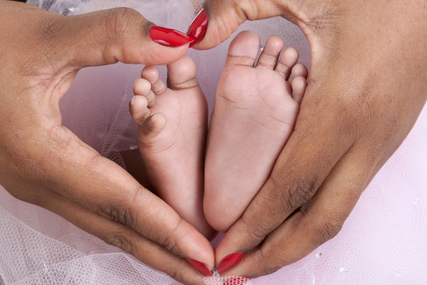 پاهای کودک در کف دست های مادر شکل قلب را با دستان مادر تشکیل می دهد استیناف صریح