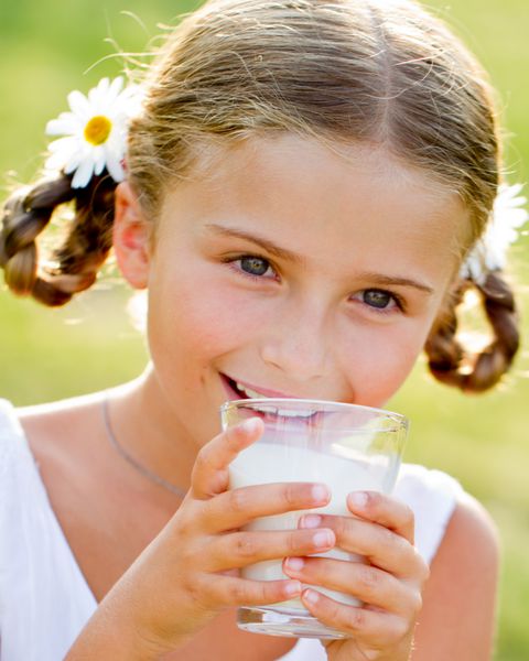 بچه سالم شیر - پرتره دختر دوست داشتنی در حال نوشیدن شیر تازه در فضای باز
