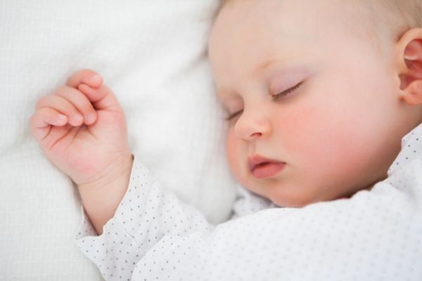 کودک دلخراشی که روی تخت دراز کشیده در حالی که در یک اتاق روشن خوابیده است