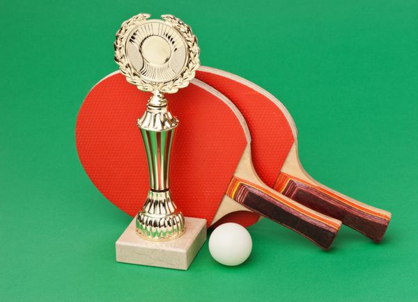 جوایز ورزشی و راکت تنیس روی میز سبز