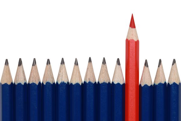 مدادهای آبی و یک مداد رنگی قرمز که از بین جمعیت برجسته است جدا شده روی سفید