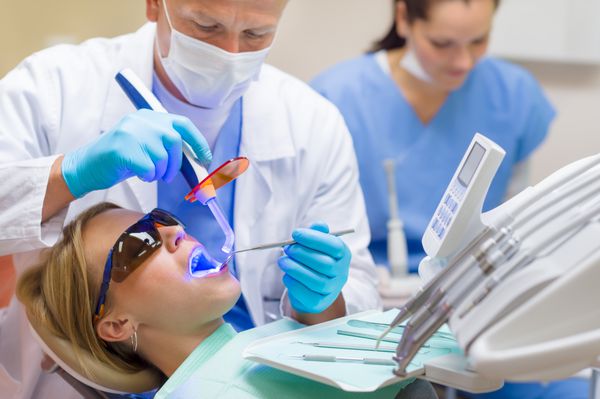 جراح ابزارهای دندانپزشکی حرفه ای از لامپ UV بیمار زن استفاده می کند