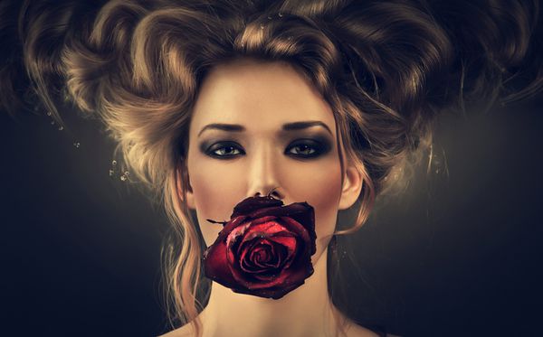 زنی با گل رز قرمز و قطره های مو در تاریکی