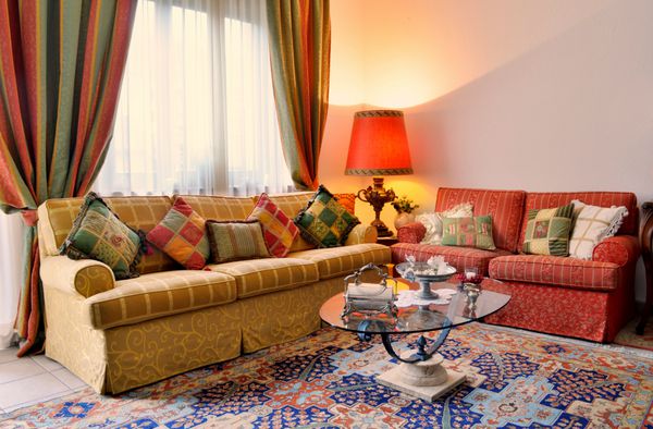 اتاق نشیمن زیبا با مبل به ظاهر کلاسیک پرده های رنگارنگ لامپ و میز شیشه ای