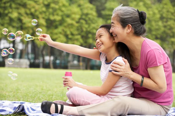 مادربزرگ چینی با نوه دختری در پارک در حال دمیدن حباب