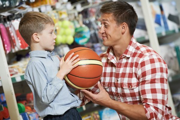 خرید خانوادگی پدر جوان با پسرش در حال انتخاب توپ سبد تجهیزات ورزشی در سوپرمارکت