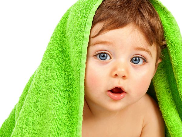 تصویر نوزاد پسر ناز پوشیده شده با حوله سبز جدا شده در پس زمینه سفید پرتره نزدیک از بچه شاد با چشمان آبی مراقبت های بهداشتی نوزاد زیبا پس از حمام کودکی شاد بهداشت کودک
