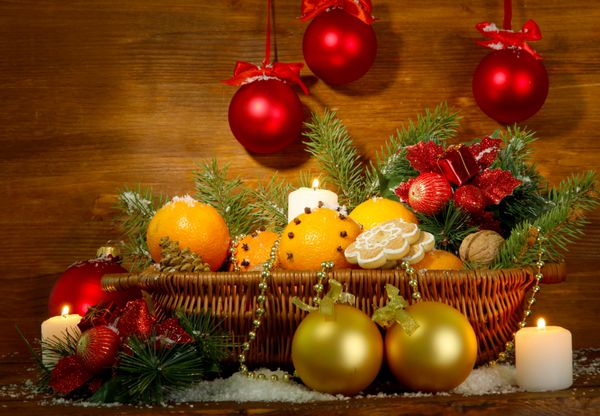 ترکیب کریسمس در سبد با پرتقال و درخت صنوبر در زمینه چوبی
