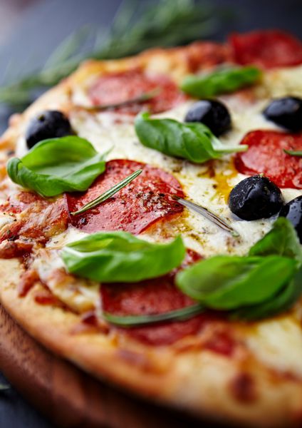 نمای نزدیک از پیتزا با سالامی و گیاهان