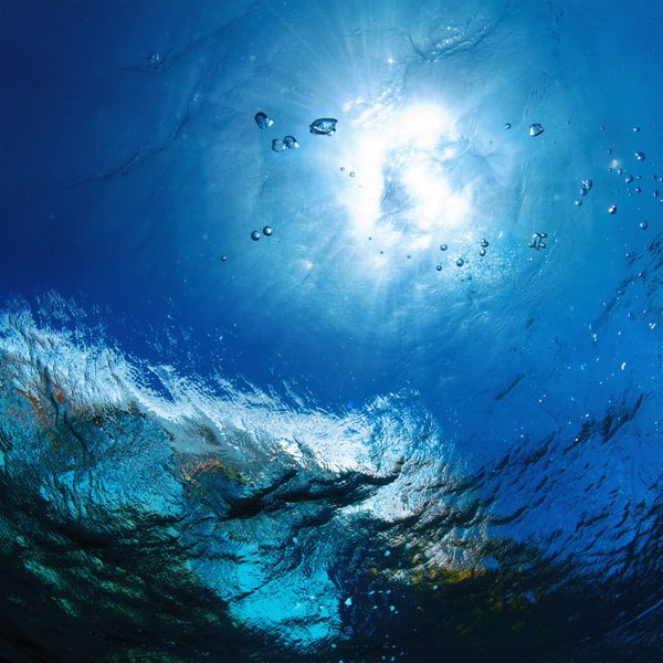 الگوی طراحی زیر آب نور خورشید در میان آب موج سواری در دریا با حباب های هوا