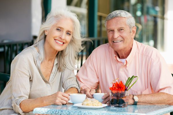 زوج سالخورده در حال لذت بردن از میان وعده در کافه در فضای باز