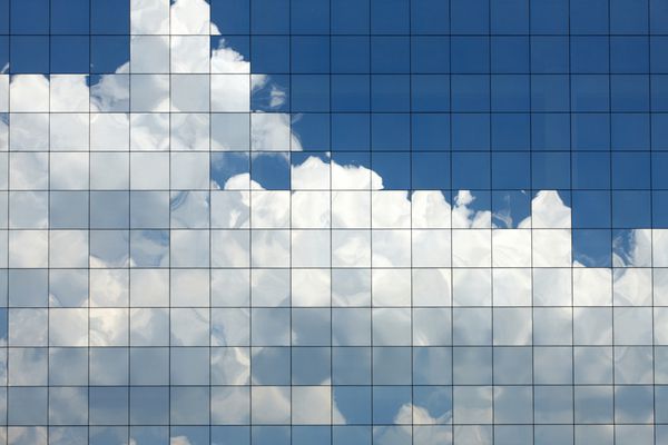 ابرهایی که در پنجره های ساختمان اداری مدرن منعکس شده اند