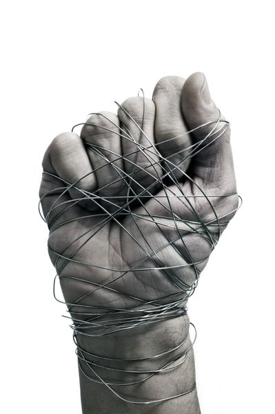 دست مردی که با سیم بسته شده است به عنوان نمادی از ظلم یا سرکوب در زمینه سفید