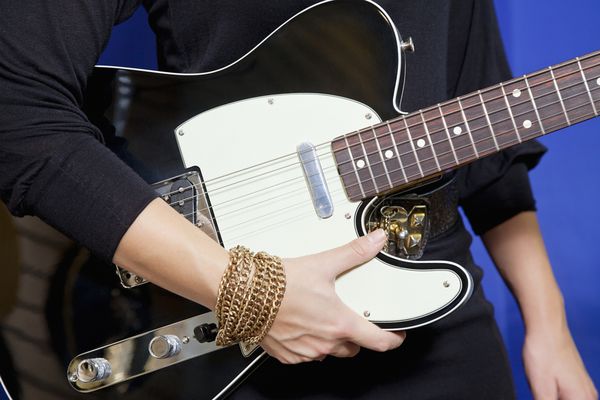 وسط زن جوانی که گیتار الکتریک در دست دارد