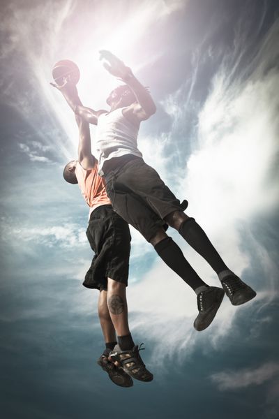 دو بسکتبالیست سبد خیابانی و پریدن با هم برای گرفتن توپ