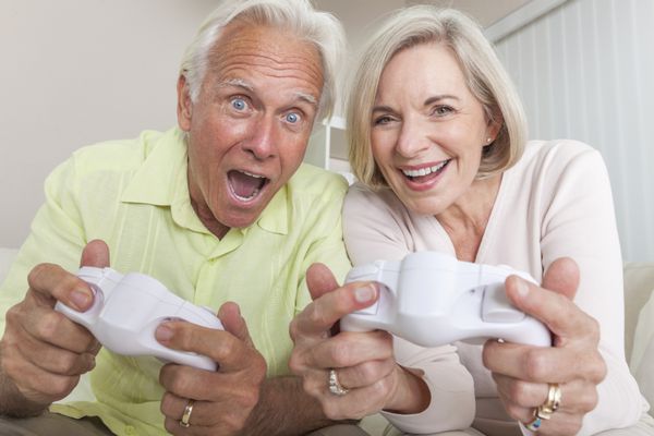 زن و شوهر سالخورده مرد و زن در حال خندیدن و داشتن بازی های سرگرم کننده کنسول های ویدئویی با هم