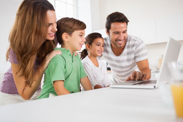 خانواده شاد با استفاده از لپ تاپ در آشپزخانه