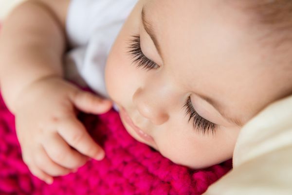 پرتره نزدیک کودک خوابیده که با پتوی بافتنی پوشیده شده است