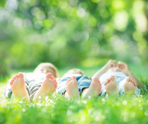 خانواده شاد دراز کشیدن روی چمن سبز در پارک بهار مفهوم سبک زندگی سالم تعطیلات زمین های کشاورزی