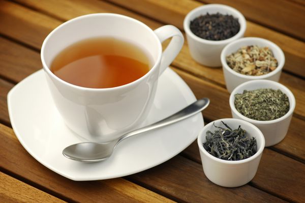 فنجان چای با انواع مختلف برگ های چای در کاسه ها