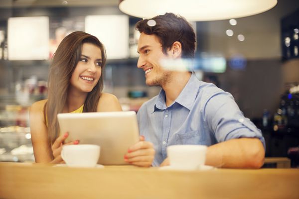زوج معاشقه در کافه با استفاده از تبلت دیجیتال