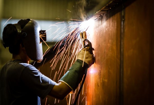 کارگر با ماسک محافظ جوش فلز و جرقه