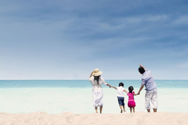 خانواده شاد در حال تفریح در ساحل در طول روز تابستان