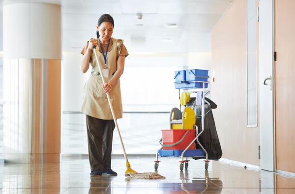 خدمتکار نظافتچی بالغ با گذرگاه راهرو تمیز کردن و نظافت یکنواخت یا کف سالن ساختمان تجاری