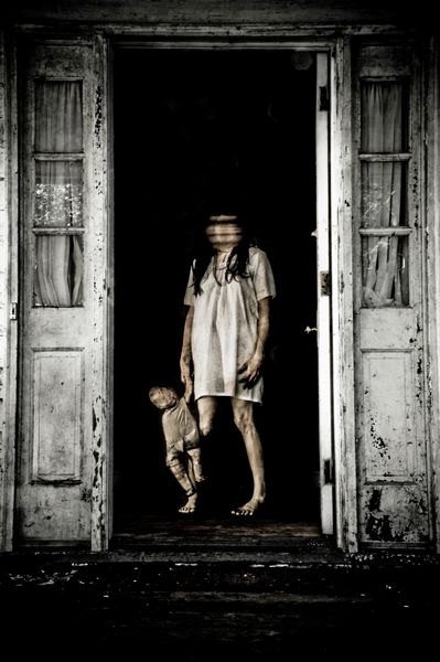 صحنه ترسناک زنی تسخیر شده با سر تار که عروسکی را در جلوی درب خانه ای قدیمی نگه داشته است