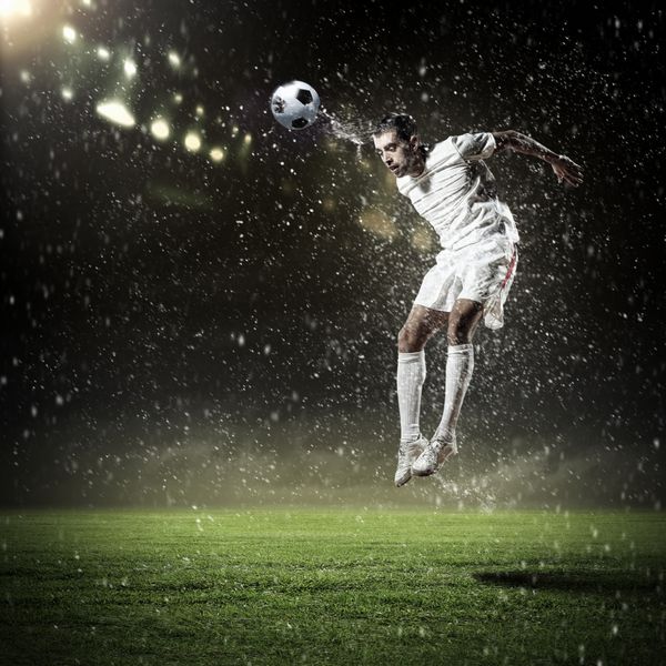تصویر بازیکن فوتبال در ورزشگاه در حال ضربه زدن به توپ