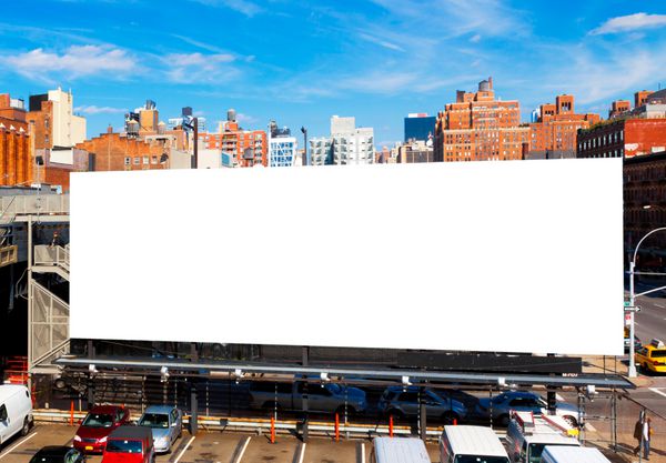 بیلبورد بزرگ خالی در شهر نیویورک احاطه شده توسط ساختمان های بلند و آسمان آبی روشن بالای سر