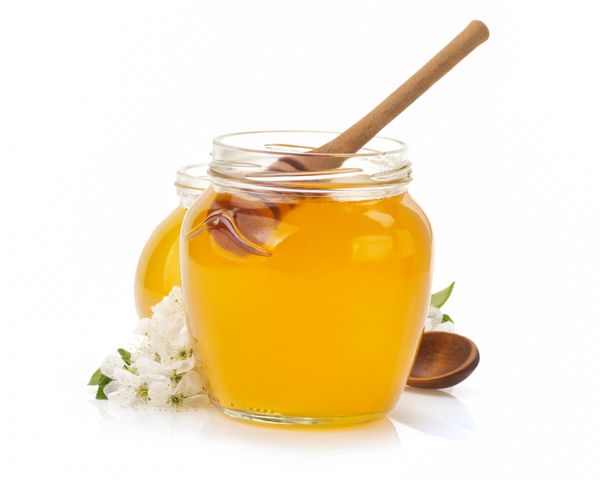 شیشه شیشه ای پر از عسل و چوب جدا شده در زمینه سفید