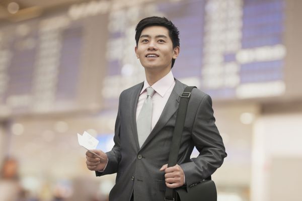 تاجر جوانی که بلیط در فرودگاه پکن چین در دست دارد